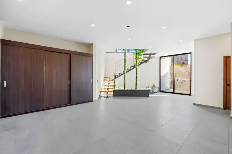 Casa de la Vista, empty room with a dark wood sliding wardrobe, a floating stair with a bamboo planter and a glass wall, San Miguel de Allende