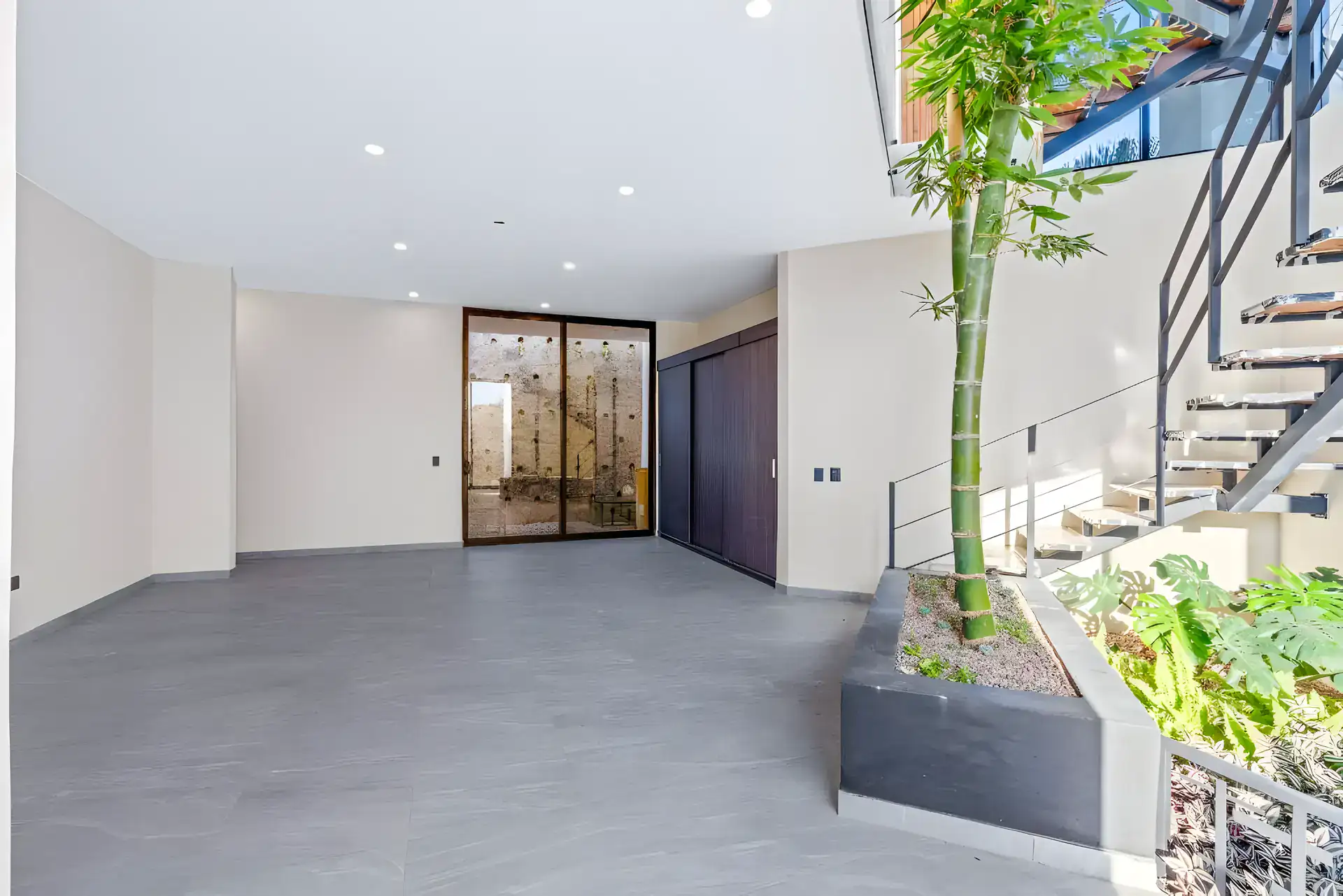 Casa de la Vista, empty room with a floating staircase, a planter with bamboo and a dark wood wardrobe, San Miguel de Allende