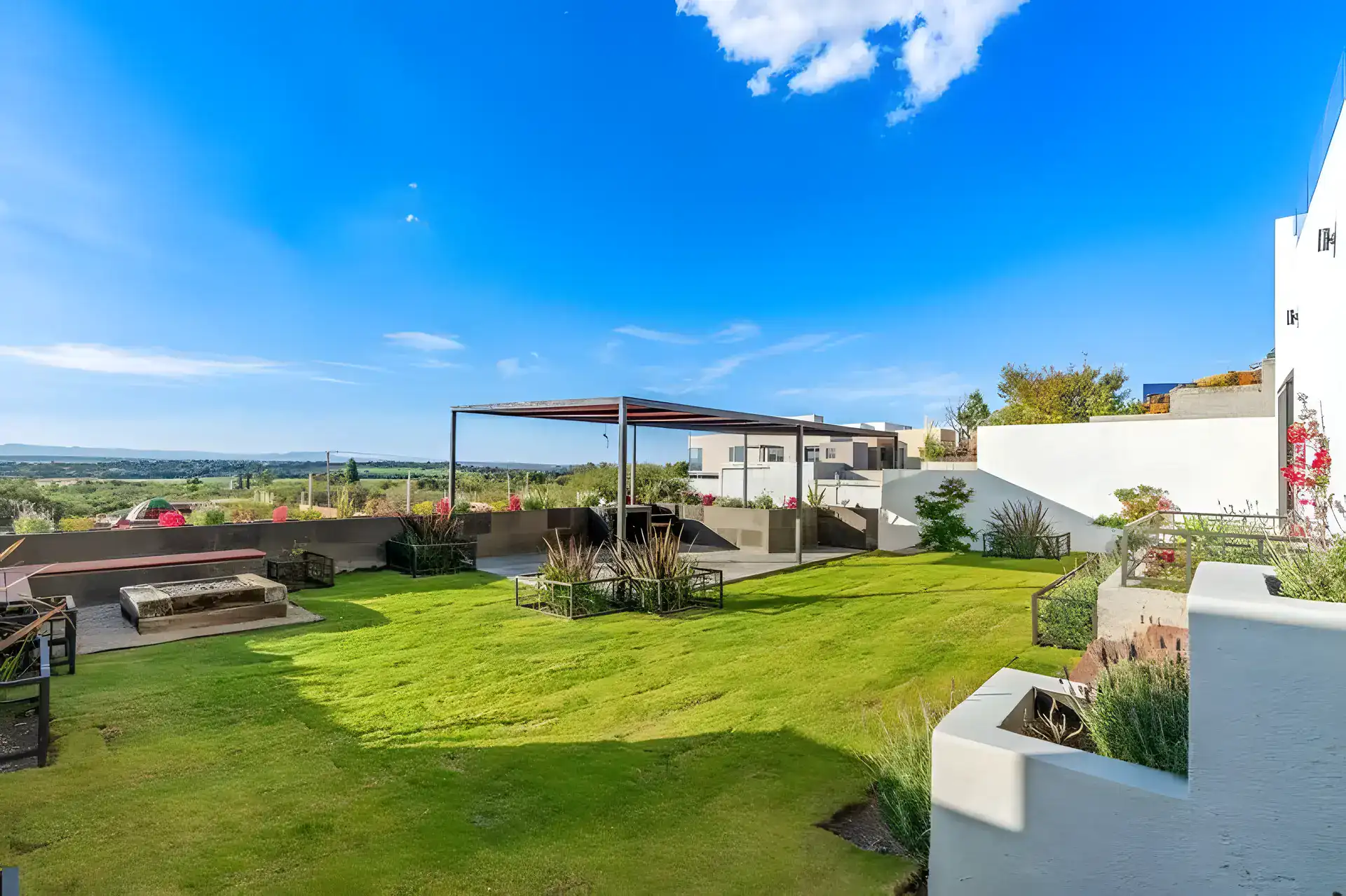 Casa de la Vista, garden with a lawn, a fire pit lounge, raised planters and the countryside beyond, San Miguel de Allende