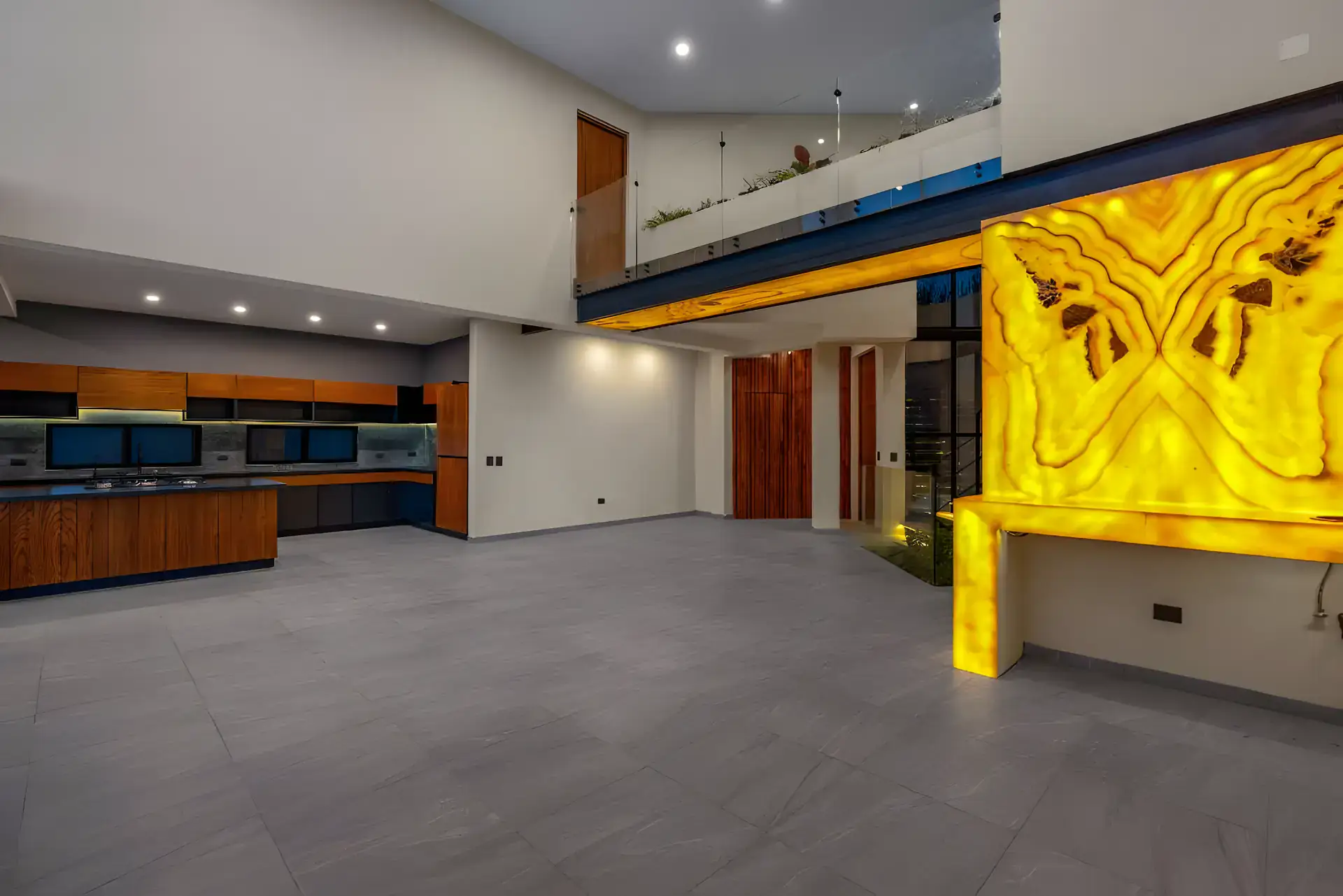 Casa de la Vista, open living and kitchen area at night with a glowing onyx wall and wood cabinets, San Miguel de Allende