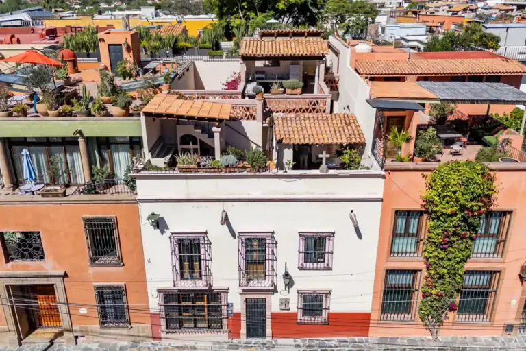 Casa de las Cruces, aerial view of the colorful street facade and terracotta-roofed rooftop terraces, San Miguel de Allende