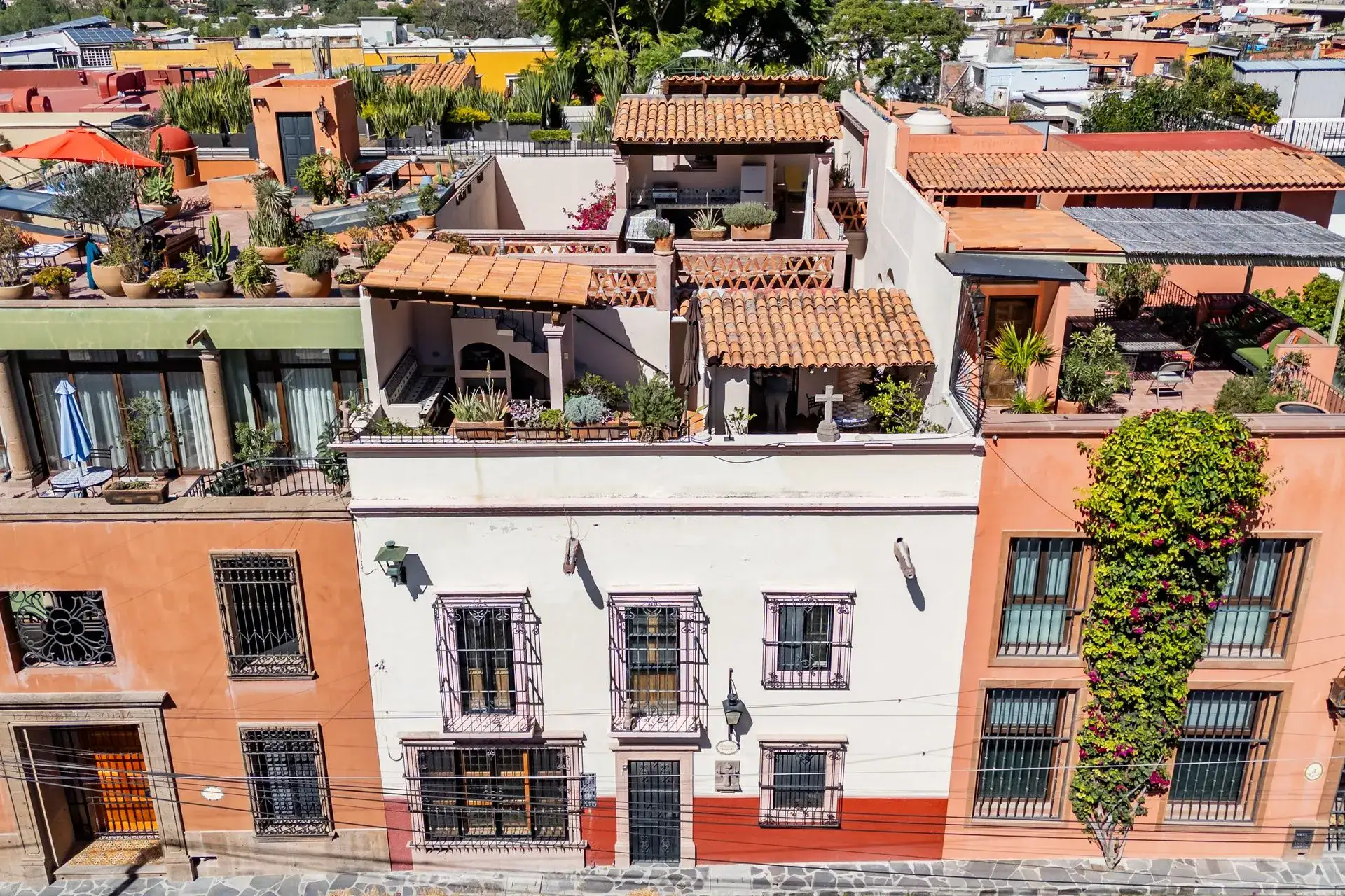 Casa de las Cruces, aerial view of the colorful street facade and terracotta-roofed rooftop terraces, San Miguel de Allende