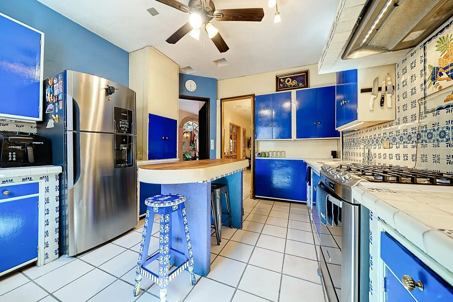Casa de las Cruces, kitchen with blue cabinets, a tiled backsplash, a stainless refrigerator and a breakfast bar with stools, San Miguel de Allende
