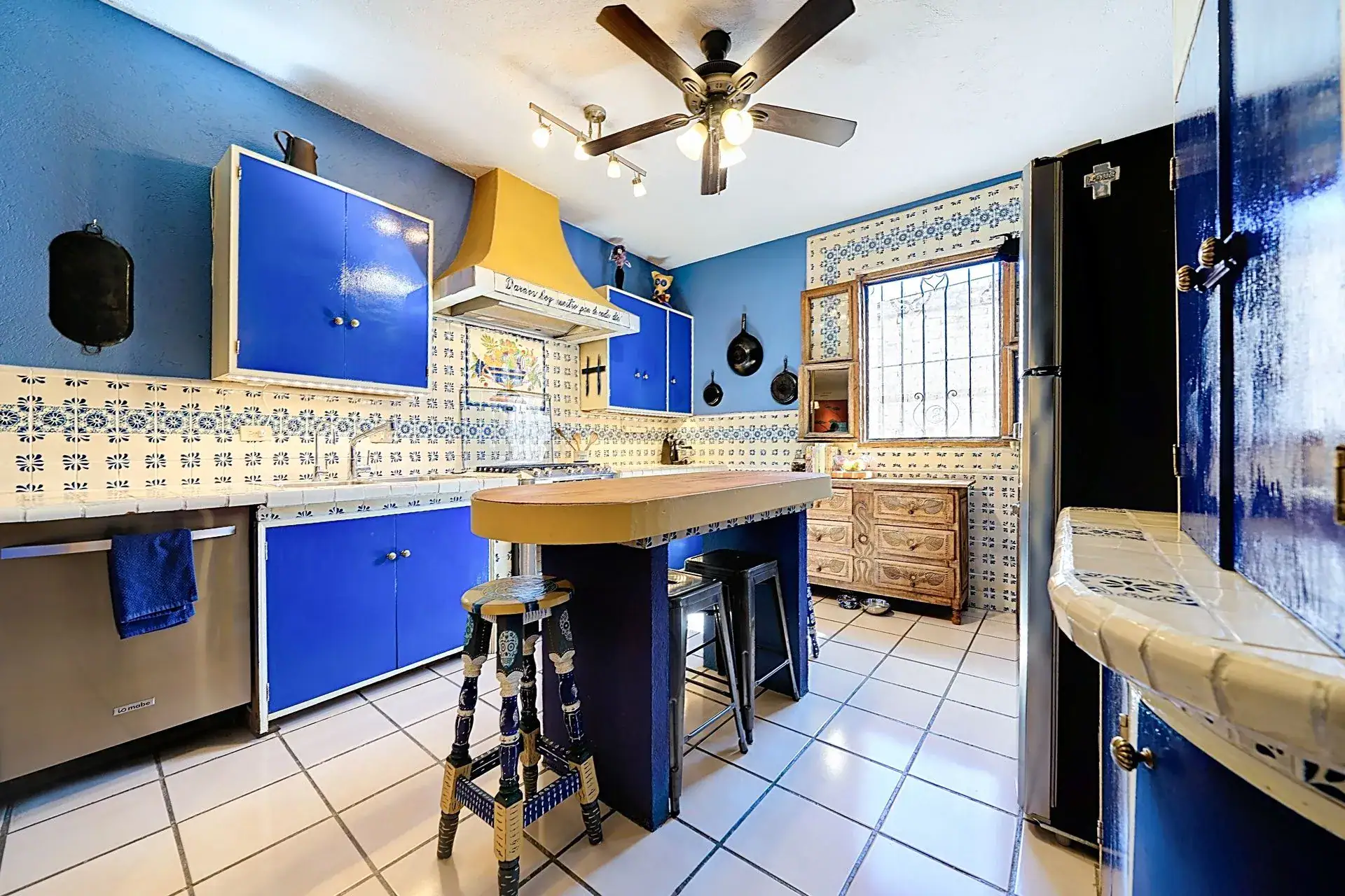 Casa de las Cruces, kitchen with a yellow range hood, blue cabinets, Talavera tile and a breakfast bar, San Miguel de Allende