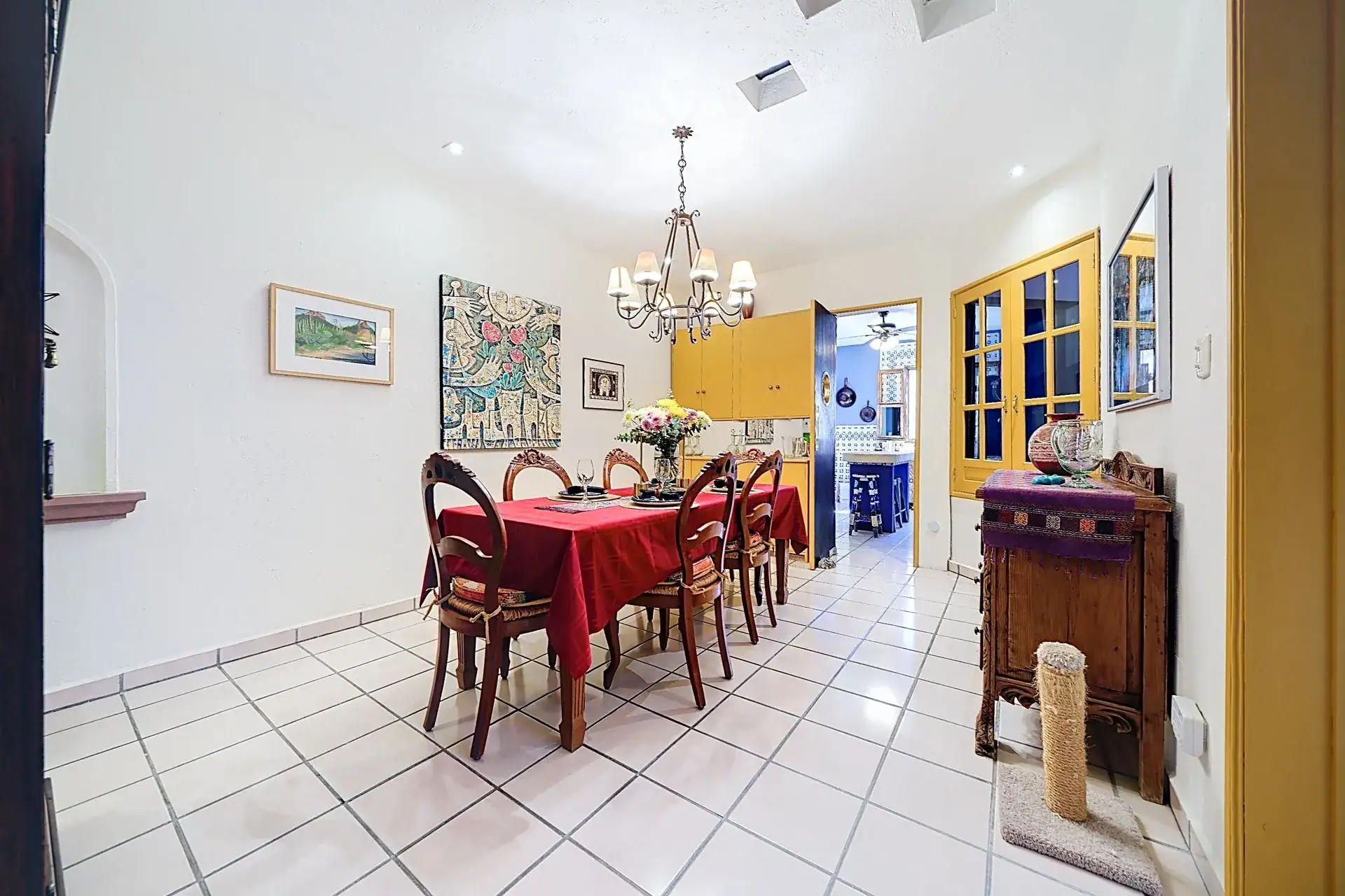 Casa de las Cruces, dining room with a red-covered table, wood chairs and a chandelier, San Miguel de Allende