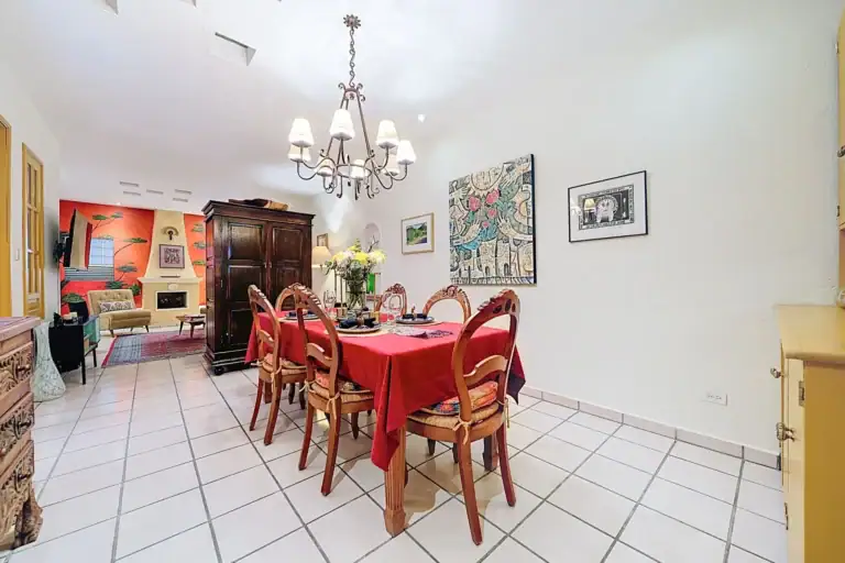 Casa de las Cruces, dining room and living room beyond with a carved armoire and colorful artwork, San Miguel de Allende