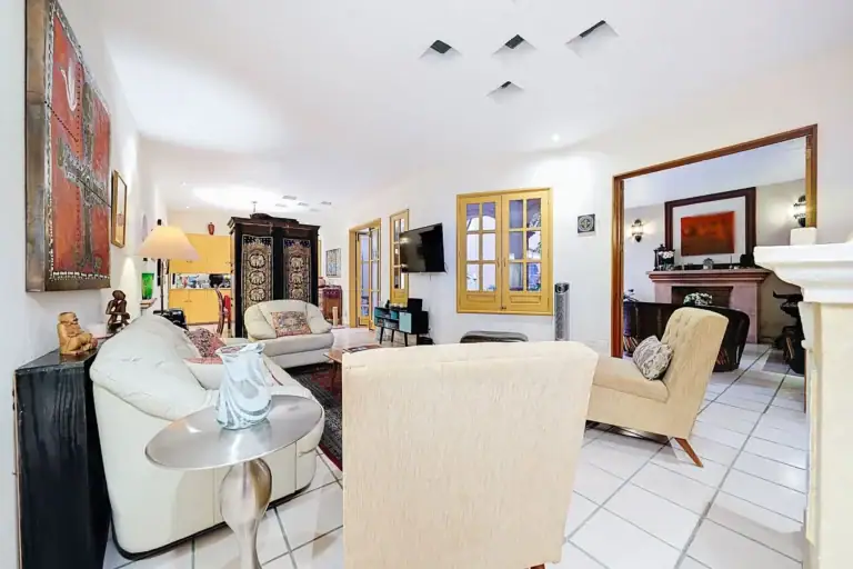 Casa de las Cruces, living room with cream leather sofas, a fireplace and a view to the dining room, San Miguel de Allende