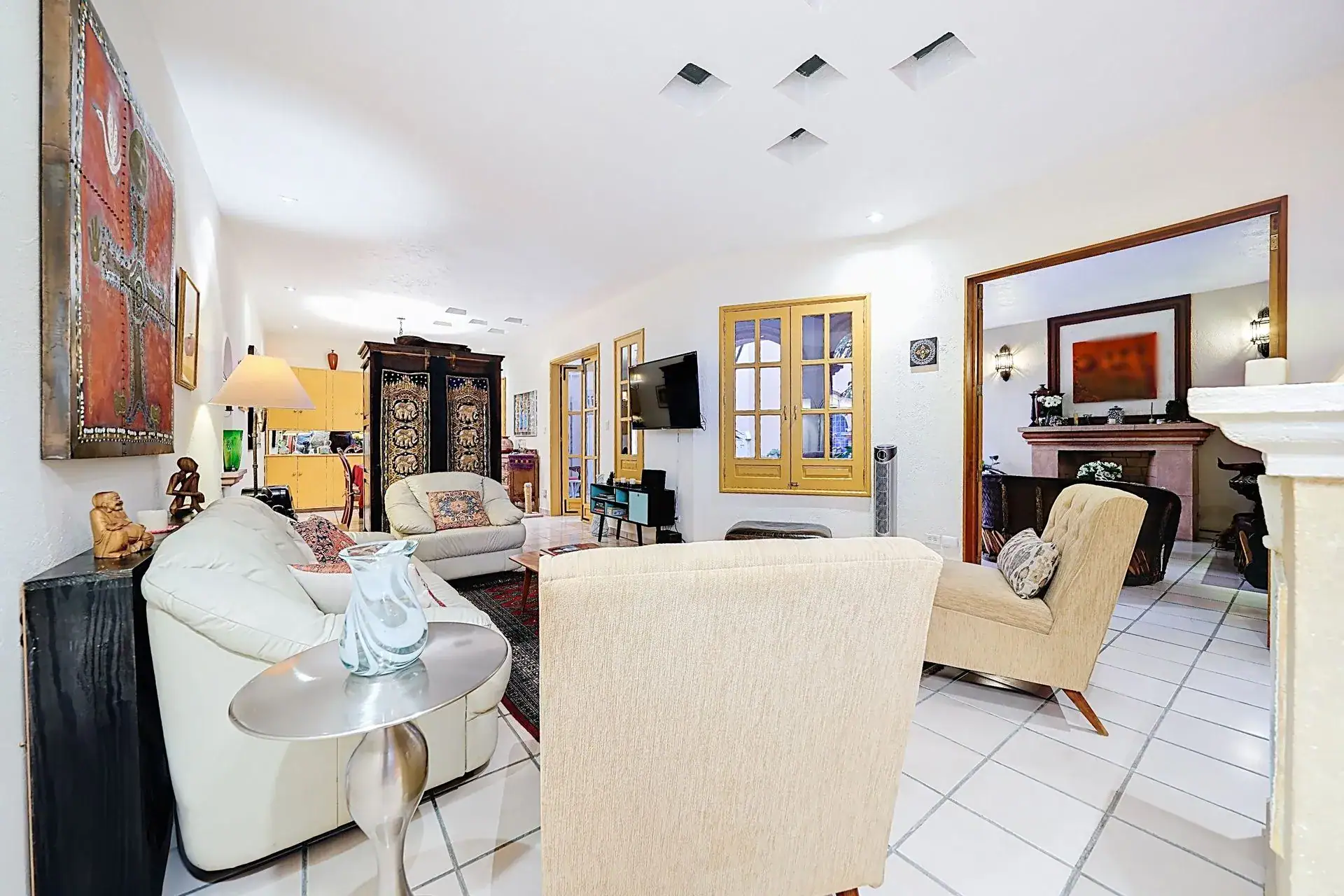 Casa de las Cruces, living room with cream leather sofas, a fireplace and a view to the dining room, San Miguel de Allende