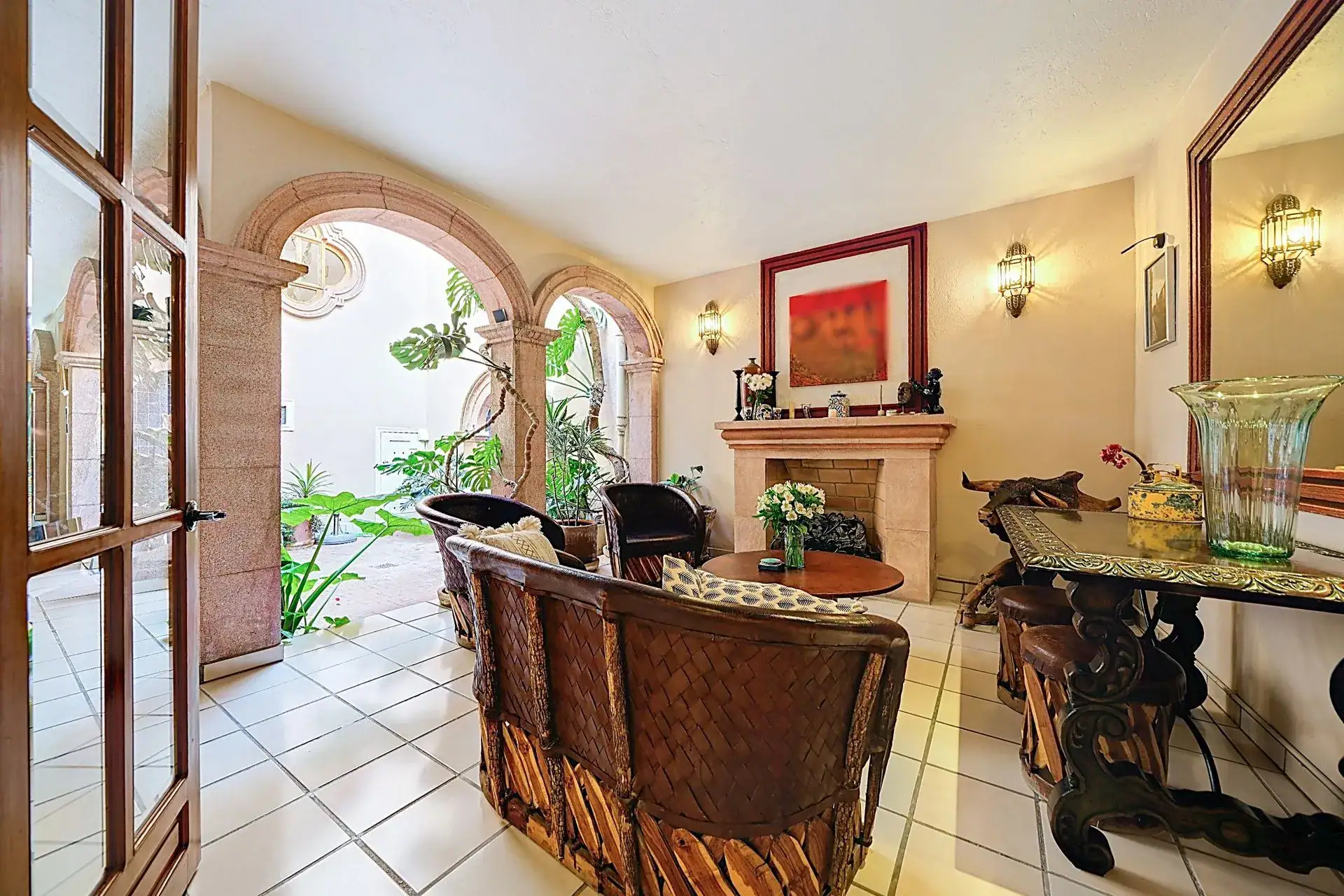 Casa de las Cruces, sitting area beside the courtyard with equipale chairs, a fireplace and arched openings, San Miguel de Allende