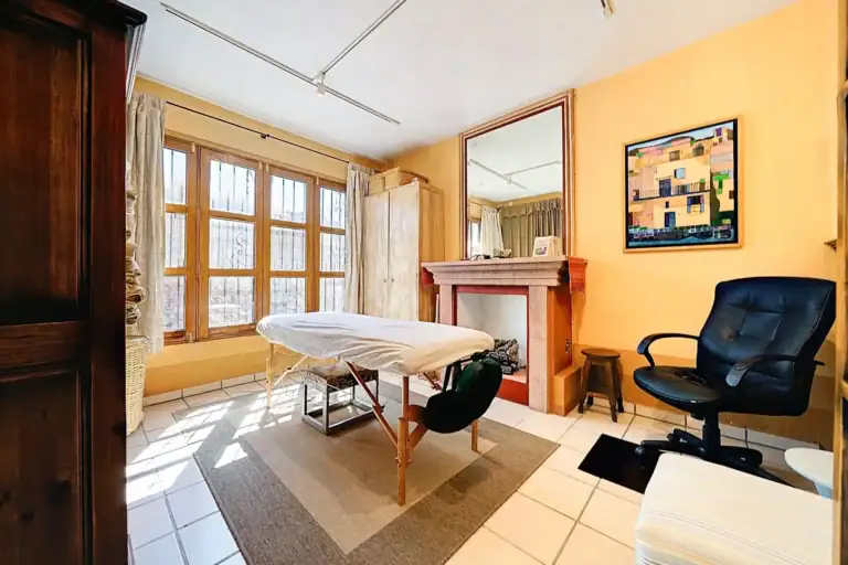 Casa de las Cruces, treatment room with a massage table, a fireplace and a tall window wall, San Miguel de Allende