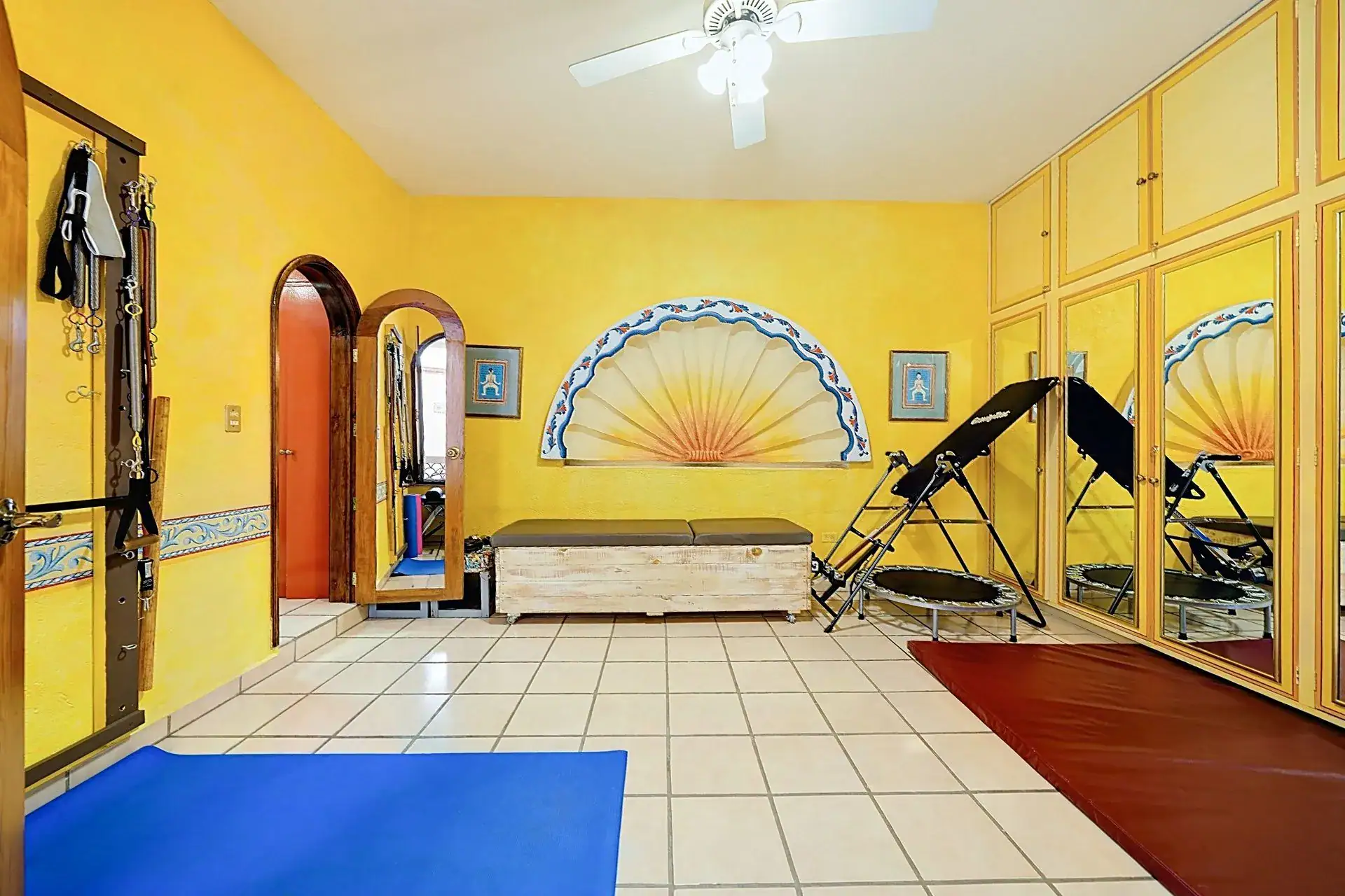 Casa de las Cruces, yellow exercise room with an inversion table, a trampoline and a painted sunburst on the wall, San Miguel de Allende