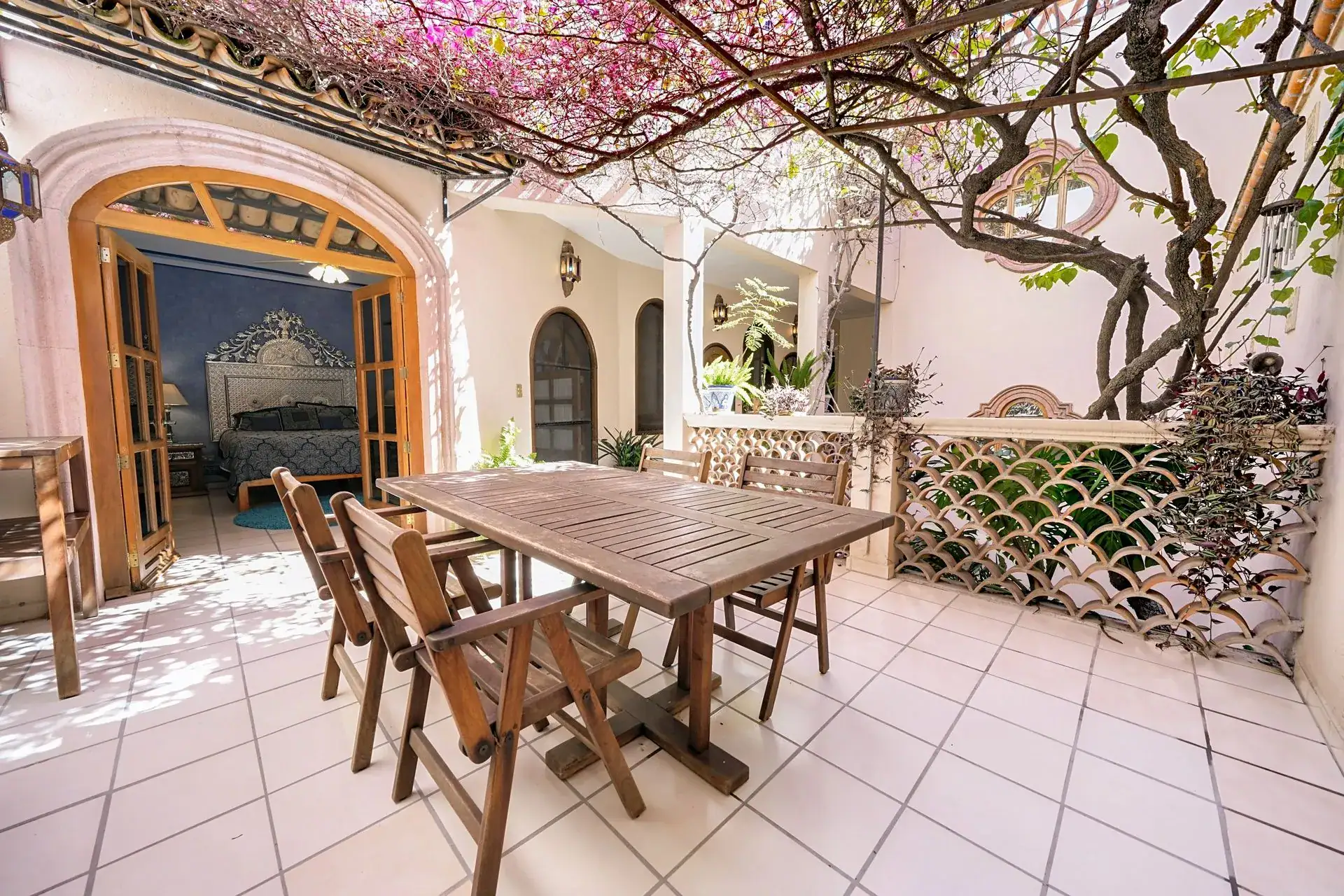 Casa de las Cruces, courtyard patio with a wood dining table and a bougainvillea-covered pergola, San Miguel de Allende