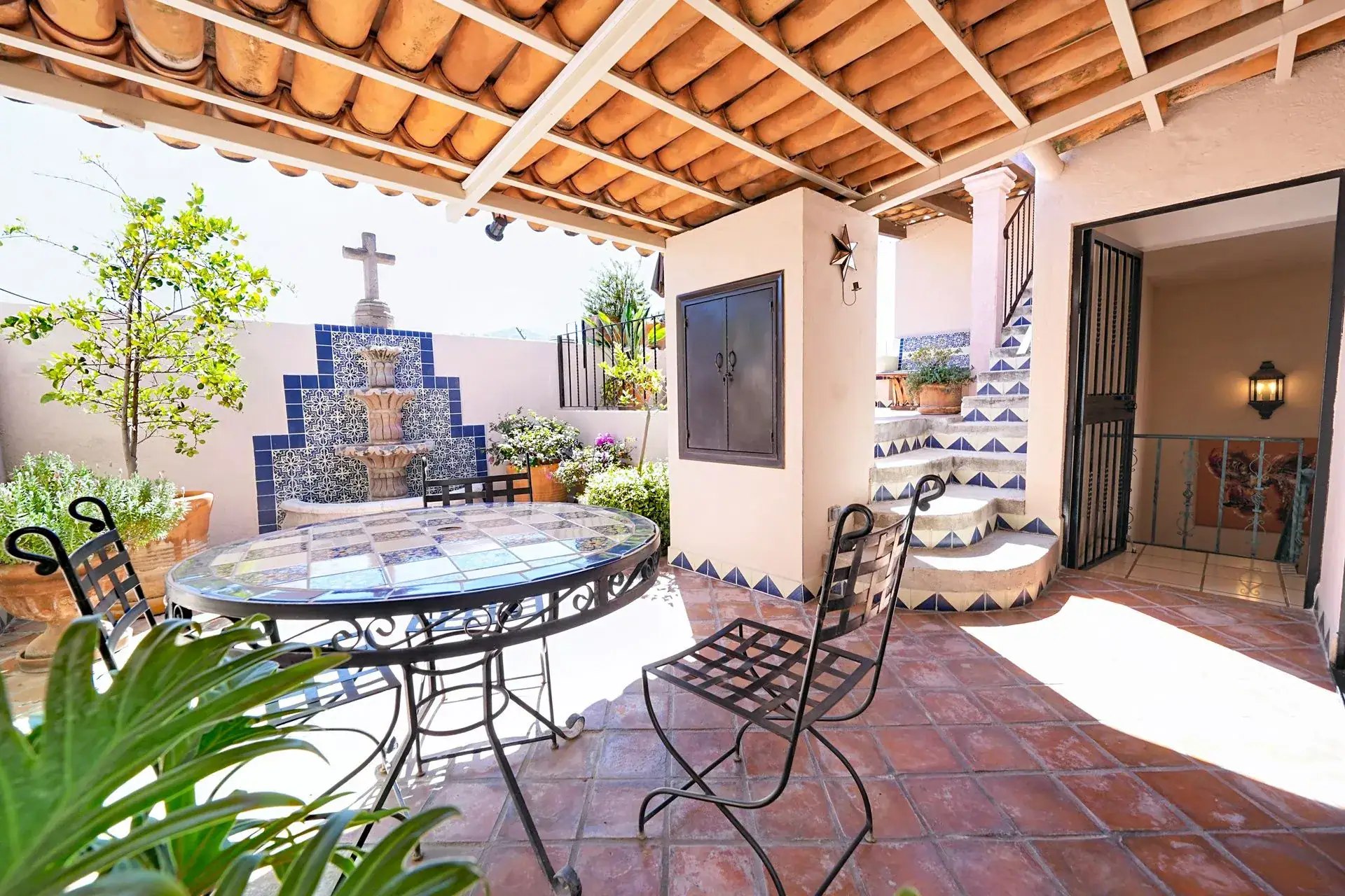 Casa de las Cruces, covered patio with a tiled round table, a stepped tile fountain with a cross and a staircase, San Miguel de Allende