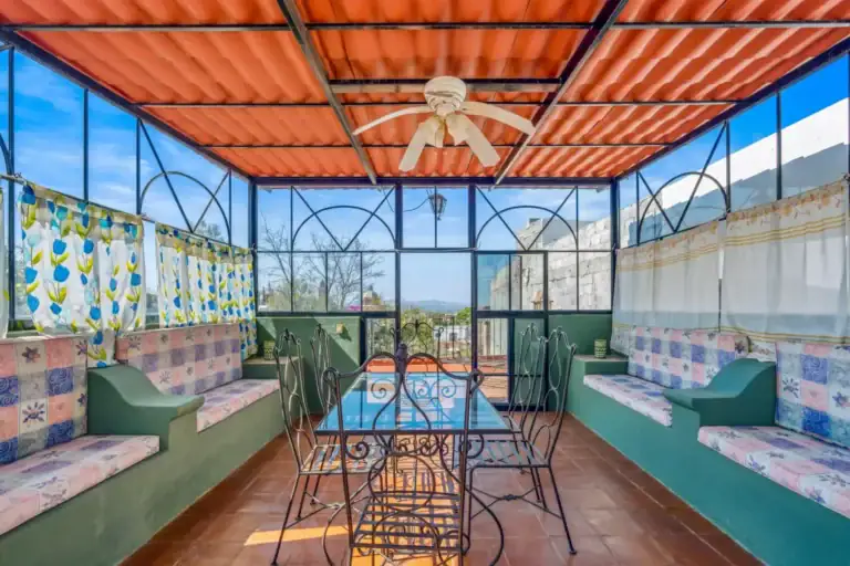 Casa de los Espejos, glassed terrace room with built-in seating and a dining table, San Miguel de Allende