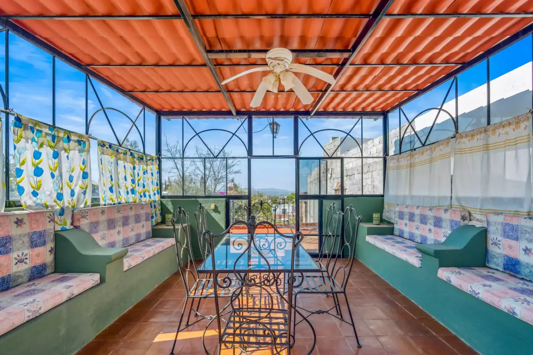 Casa de los Espejos, glassed terrace room with built-in seating and a dining table, San Miguel de Allende