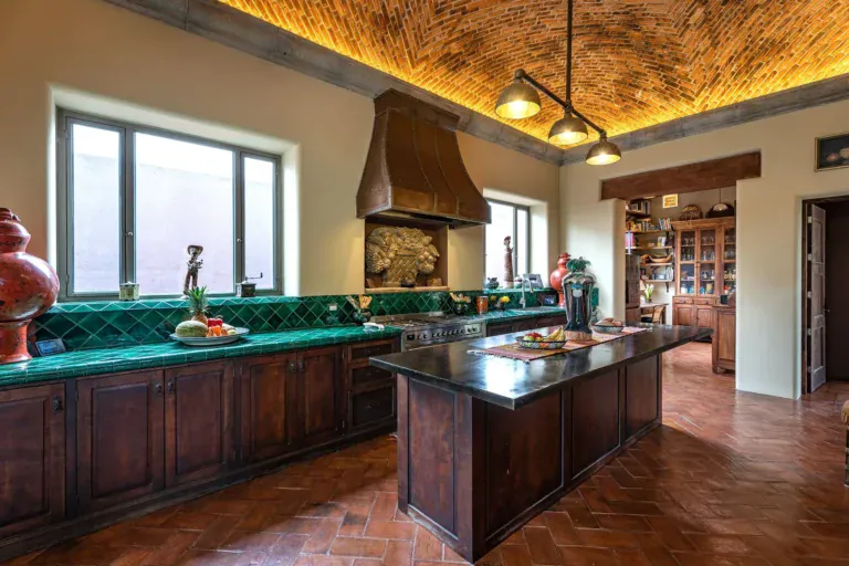 Casa de Salca, kitchen with green tile counters, a wood island and a copper hood, San Miguel de Allende