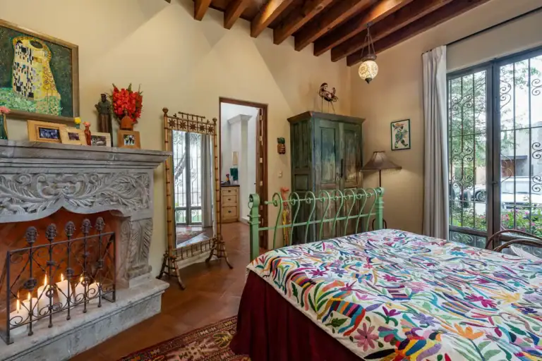 Casa de Salca, bedroom with a fireplace and a colorful embroidered bedspread, San Miguel de Allende