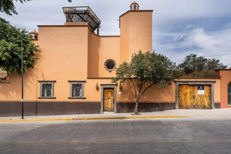 Casa DeeDee, orange stucco corner house with arched doors and a rooftop tower, San Miguel de Allende