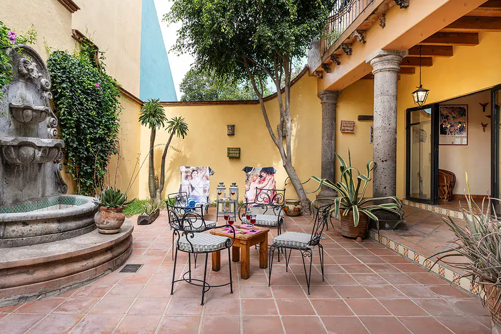 Casa DeeDee, courtyard with a stone fountain and iron chairs under a covered gallery, San Miguel de Allende