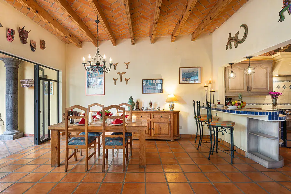 Casa DeeDee, dining room with a wood table, a chandelier and carved posts, San Miguel de Allende
