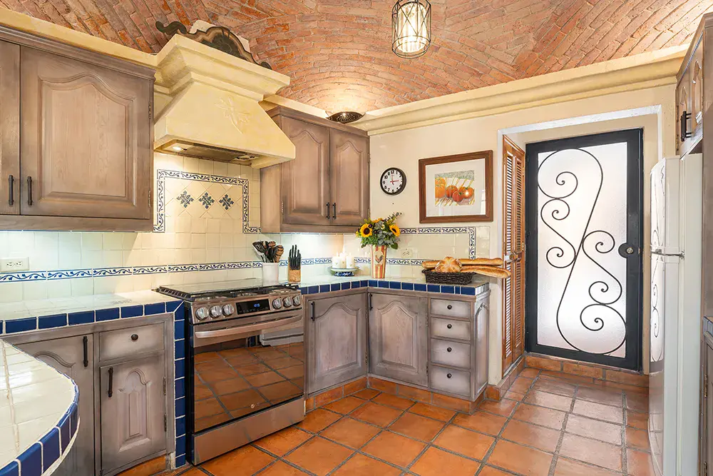 Casa DeeDee, kitchen with blue tile counters, wood cabinets and a wrought-iron door, San Miguel de Allende