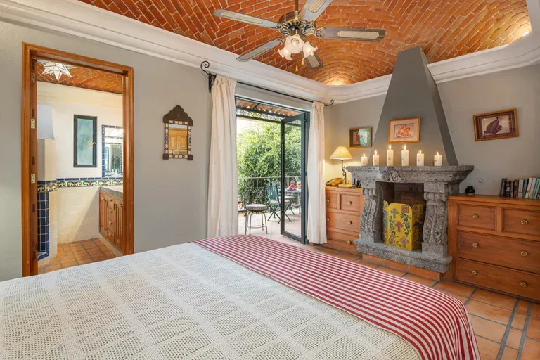 Casa DeeDee, bedroom with a corner stone fireplace and a ceiling fan, San Miguel de Allende
