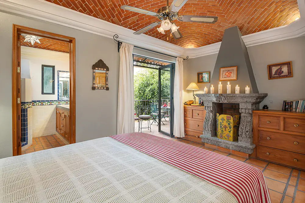 Casa DeeDee, bedroom with a corner stone fireplace and a ceiling fan, San Miguel de Allende