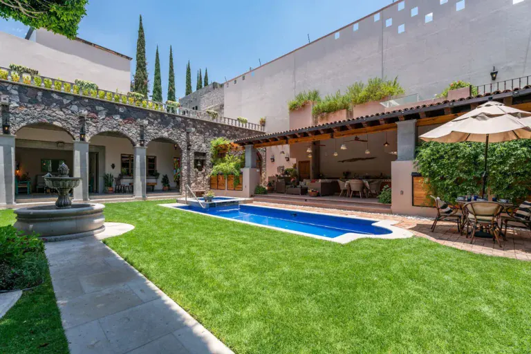 Casa del Angel, courtyard lawn with a stone fountain, a pool and a stone arcade, San Miguel de Allende