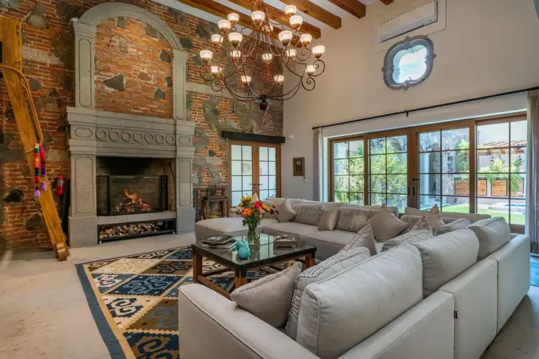 Casa del Angel, living room with a stone fireplace, a sectional sofa and a crystal chandelier, San Miguel de Allende