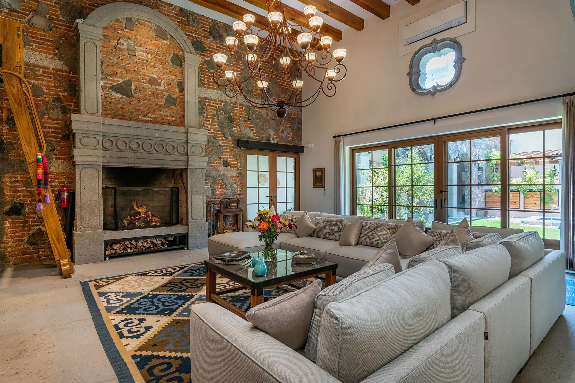 Casa del Angel, living room with a stone fireplace, a sectional sofa and a crystal chandelier, San Miguel de Allende