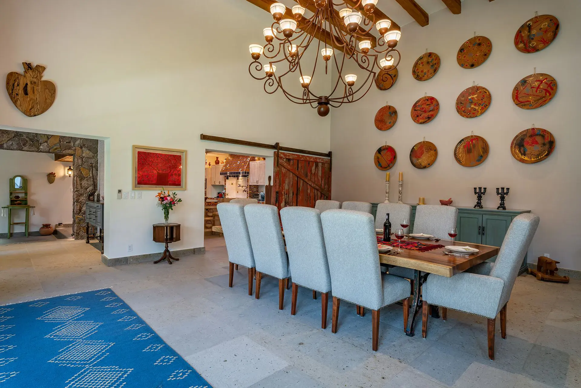 Casa del Angel, dining room with white chairs, clay plates on the wall and a chandelier, San Miguel de Allende