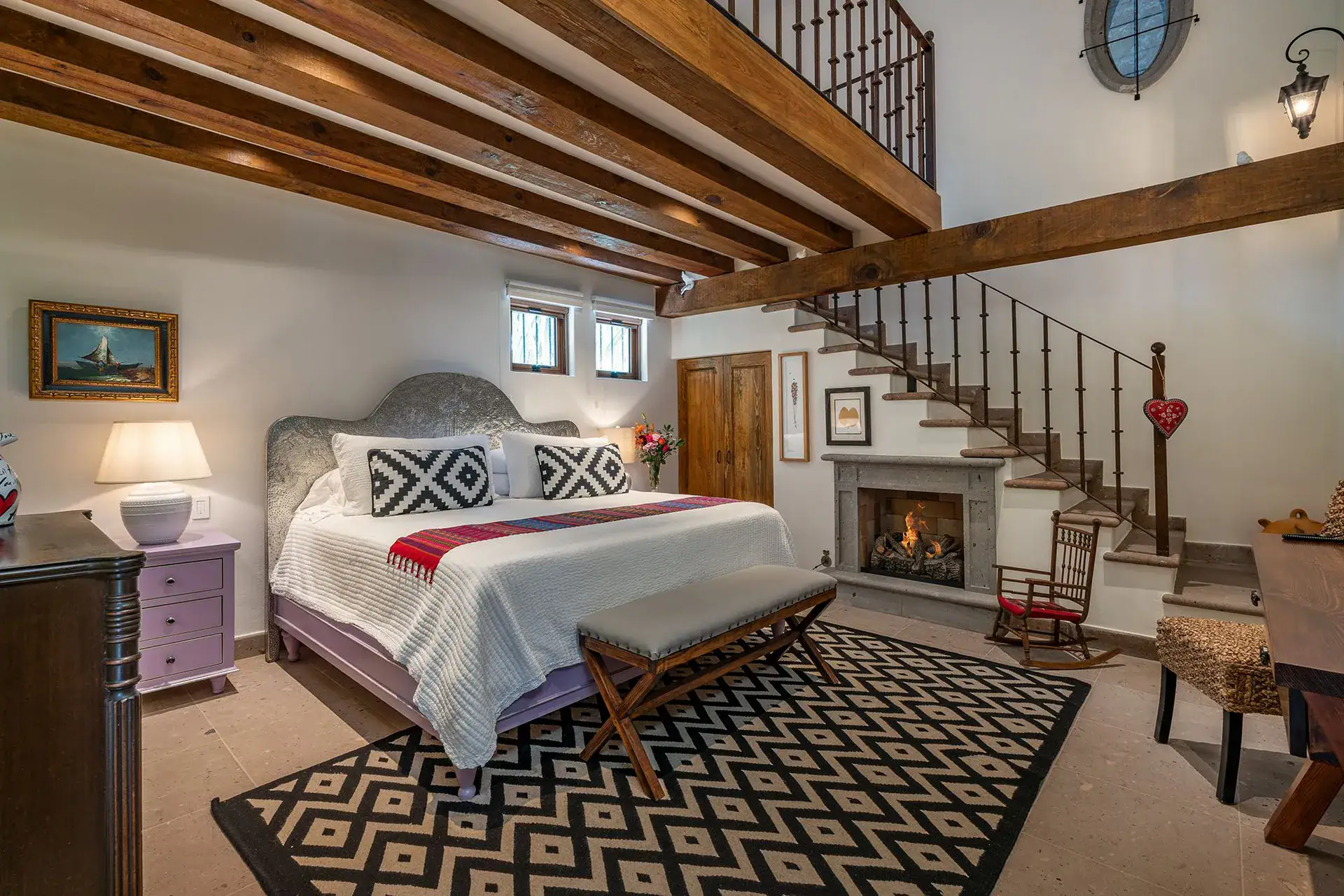 Casa del Angel, primary bedroom with a fireplace, a patterned rug and a staircase, San Miguel de Allende