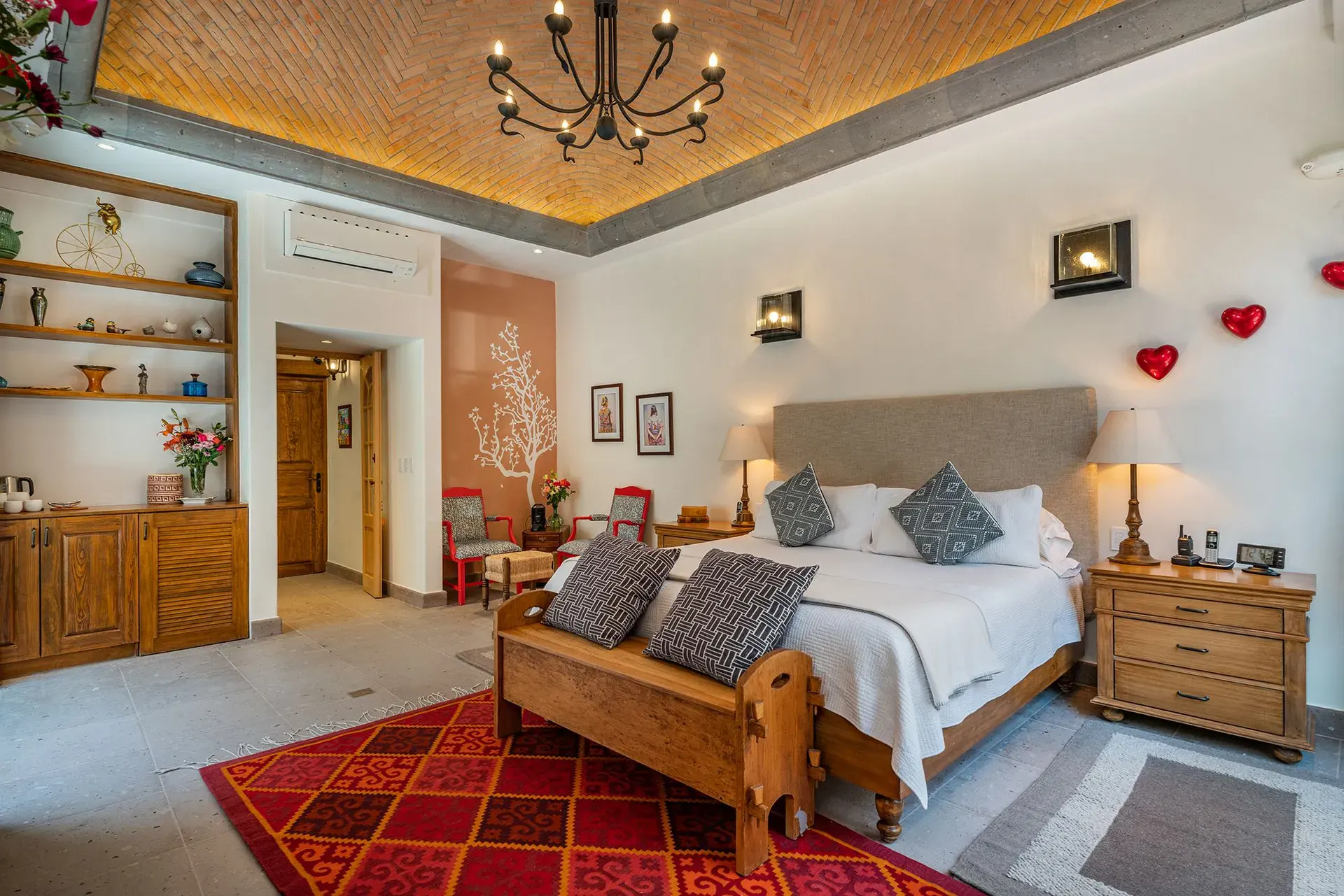 Casa del Angel, bedroom with a wood bed, a red rug and a brick vaulted ceiling, San Miguel de Allende