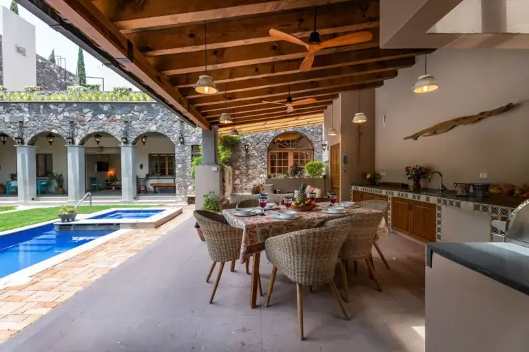 Casa del Angel, covered terrace with a dining table, wicker chairs and a view of the pool, San Miguel de Allende
