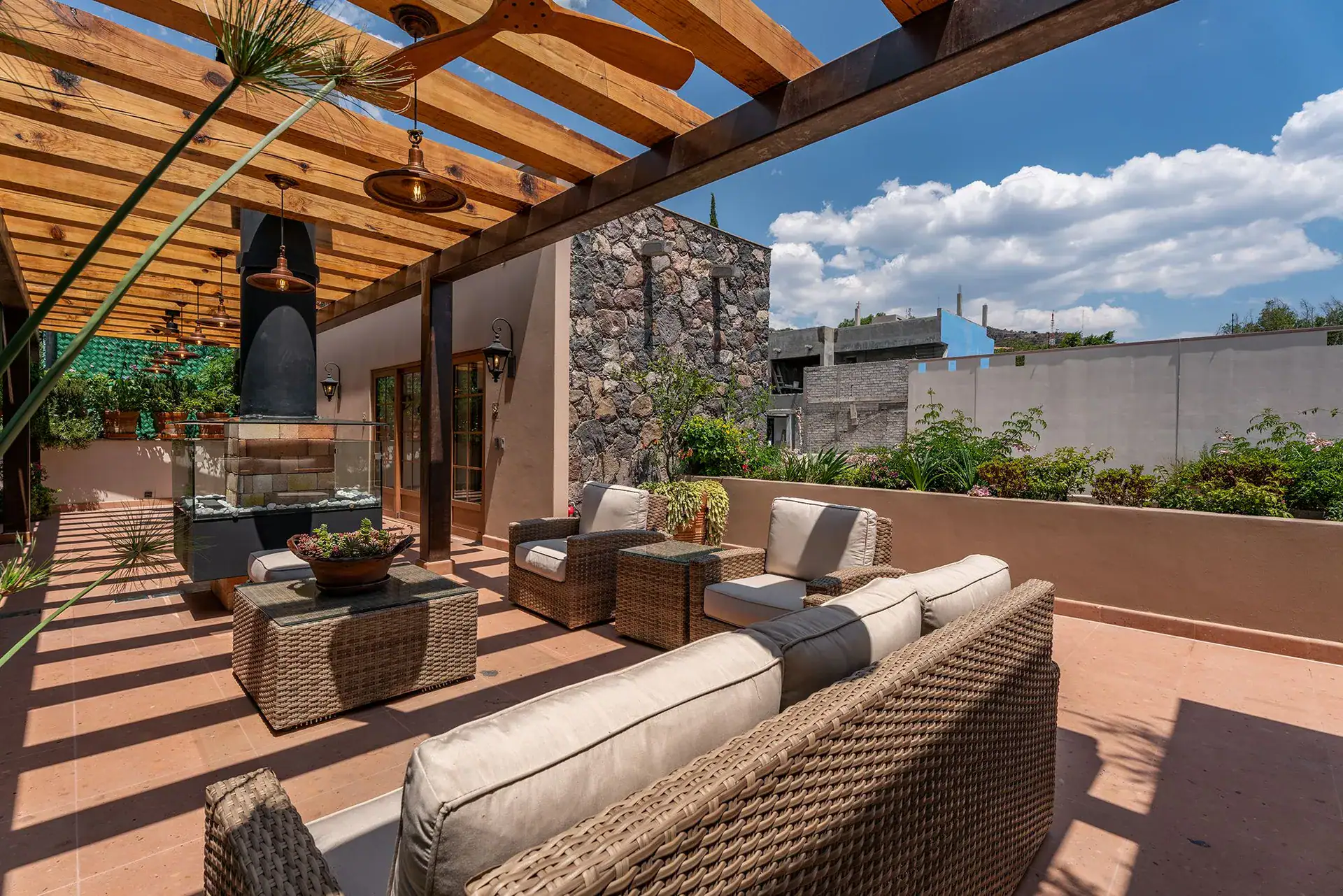 Casa del Angel, rooftop terrace with wicker sofas under a wood pergola, San Miguel de Allende