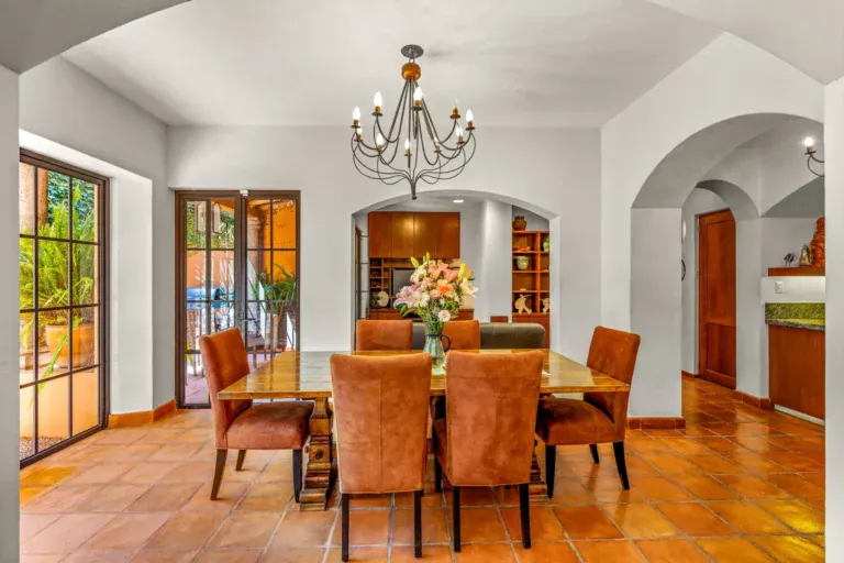 Casa del Artista, dining room with a wood table, suede chairs, an iron chandelier and arched passages, San Miguel de Allende