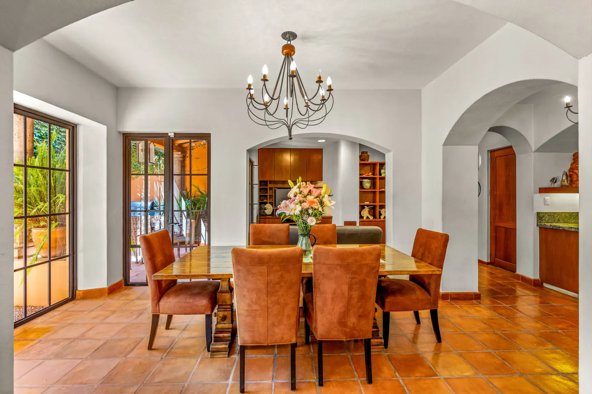 Casa del Artista, dining room with a wood table, suede chairs, an iron chandelier and arched passages, San Miguel de Allende