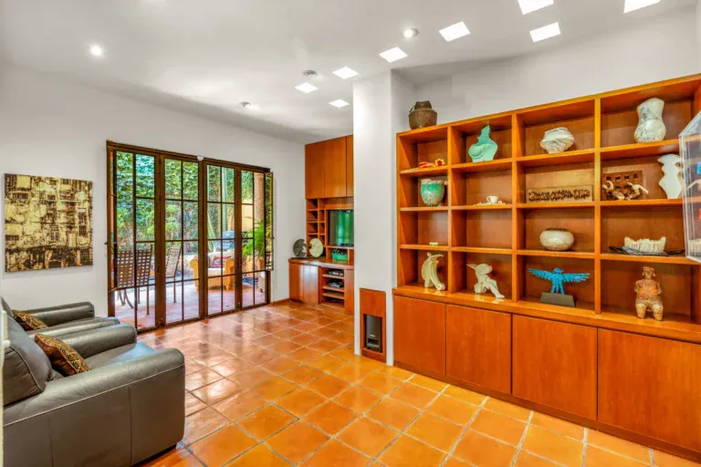 Casa del Artista, den with leather armchairs, a wall of wood shelves with ceramics and glass doors to the patio, San Miguel de Allende