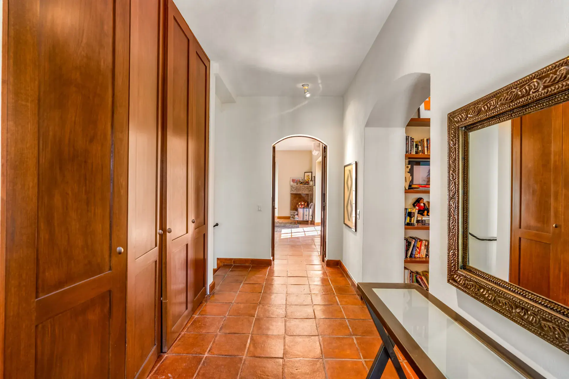 Casa del Artista, hallway with wood closets, a gilt mirror, a console table and an arched view to a bedroom, San Miguel de Allende