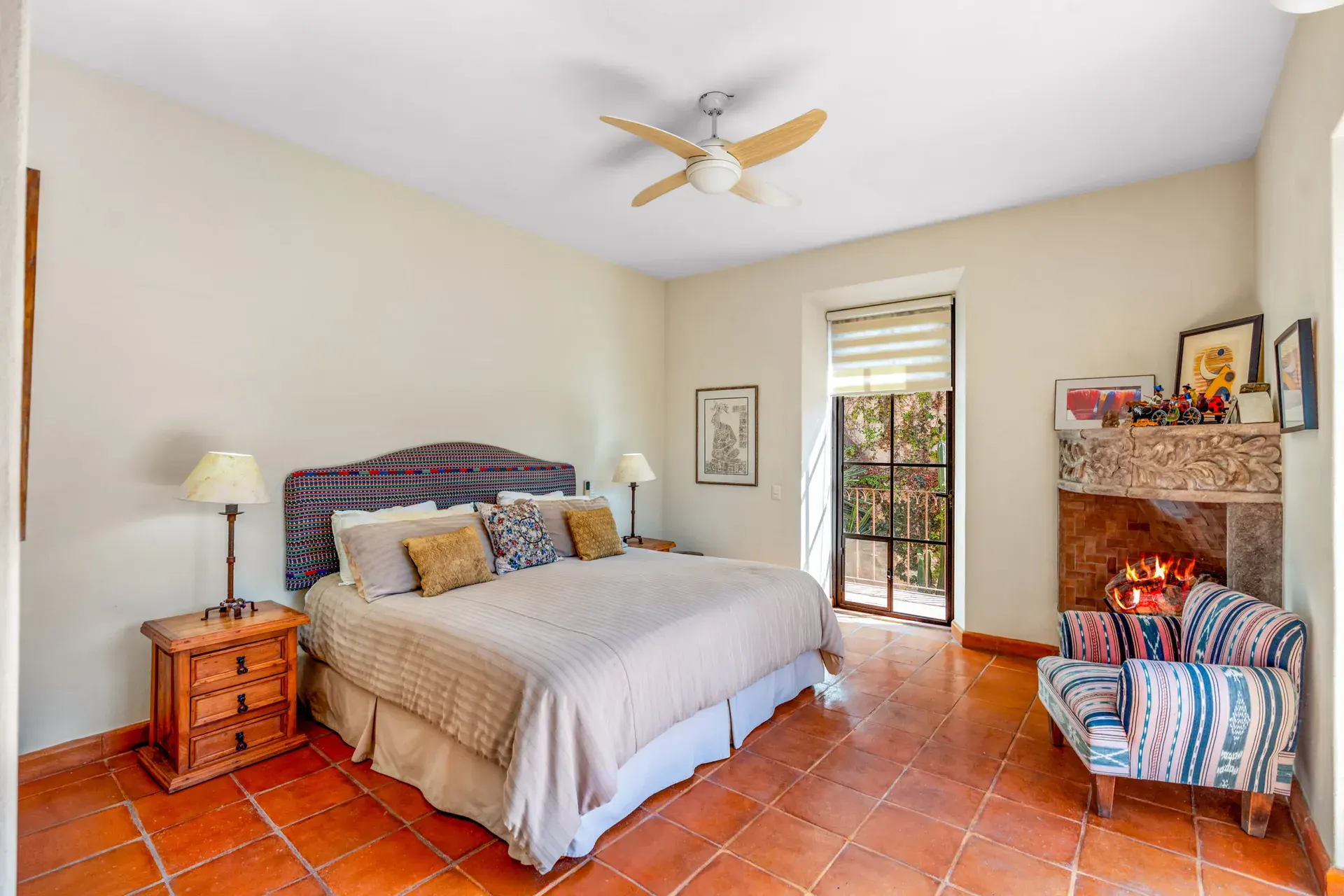 Casa del Artista, bedroom with a purple headboard, a carved stone fireplace and striped armchairs, San Miguel de Allende