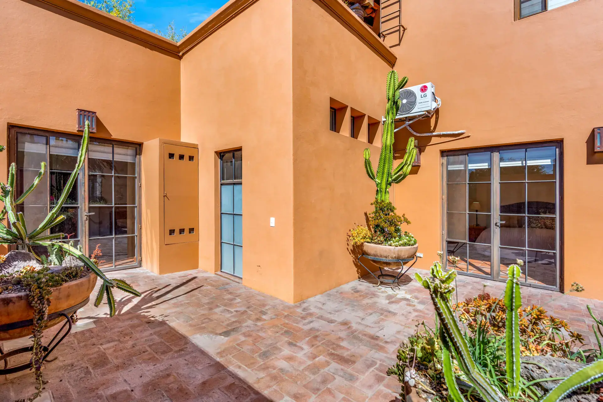 Casa del Artista, brick patio with potted cactus and French doors to a bedroom, San Miguel de Allende