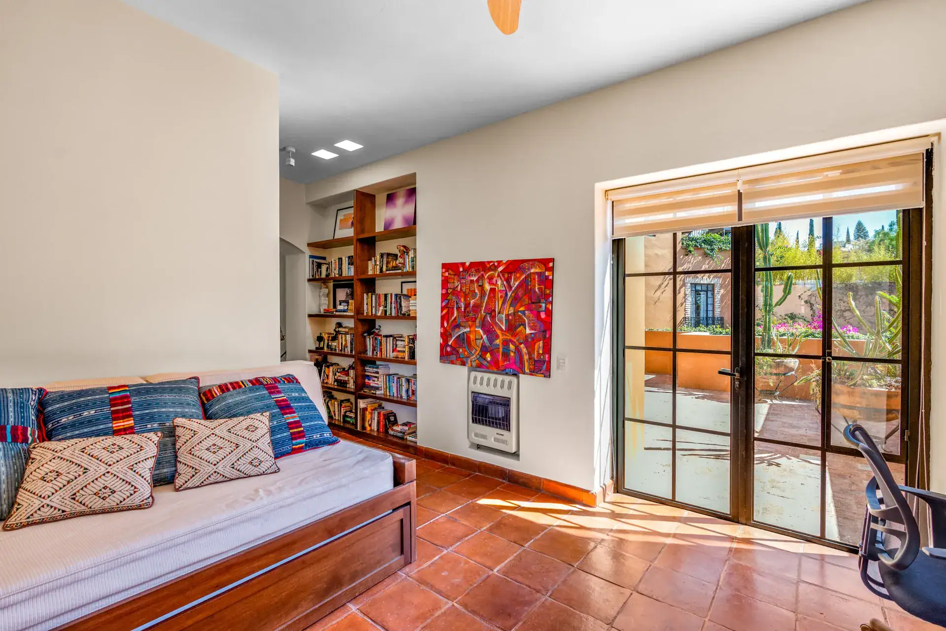 Casa del Artista, office with a daybed with blue and red pillows, bookshelves and glass doors to the patio, San Miguel de Allende