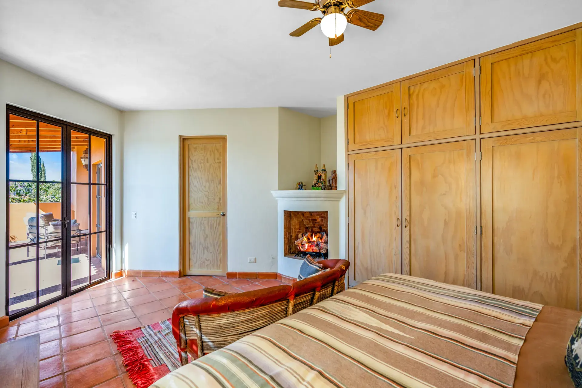 Casa del Artista, bedroom with a corner fireplace, wood wardrobes and glass doors to a patio, San Miguel de Allende