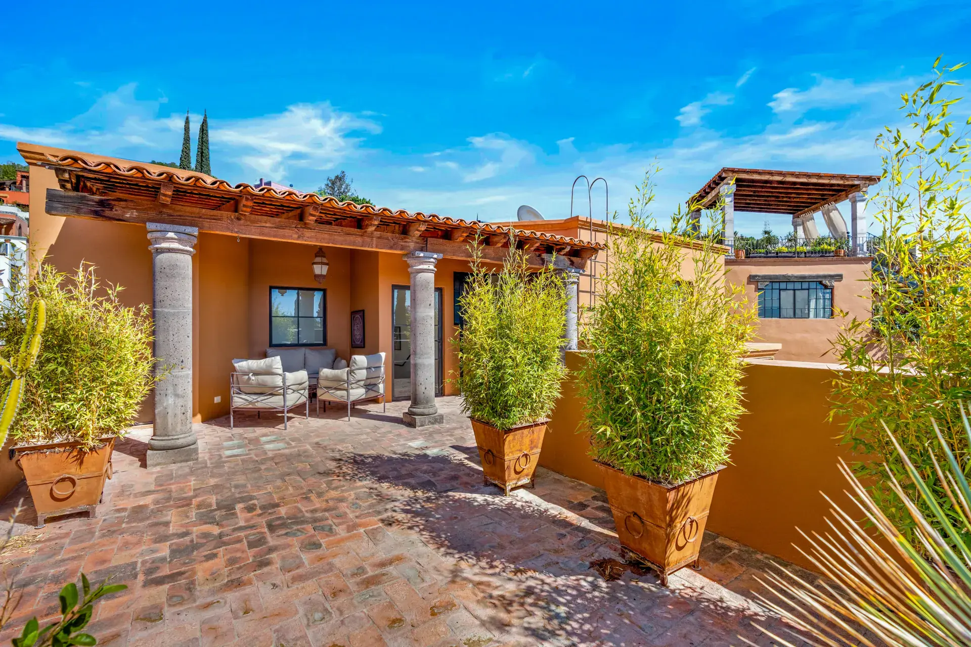 Casa del Artista, rooftop terrace with a tile-roofed pavilion, brick paving and bamboo in clay pots, San Miguel de Allende