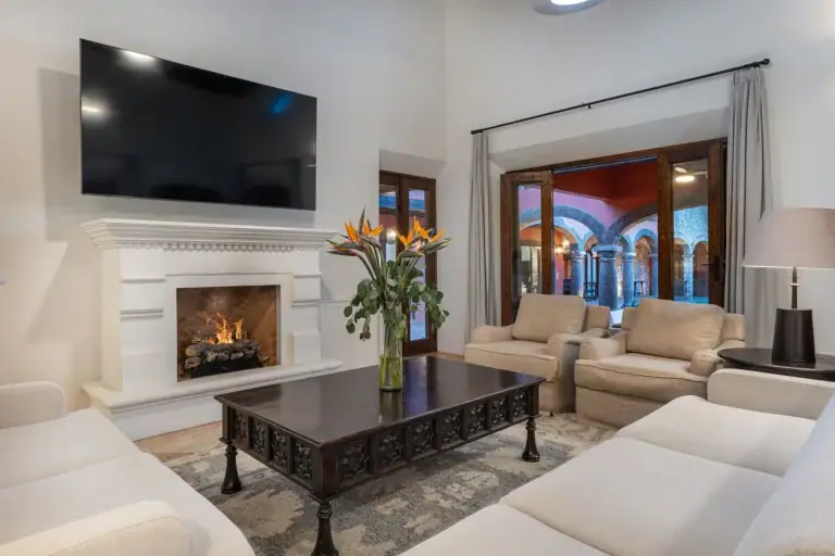 Casa Del Cardo, living room with a white fireplace and a wall-mounted television, San Miguel de Allende