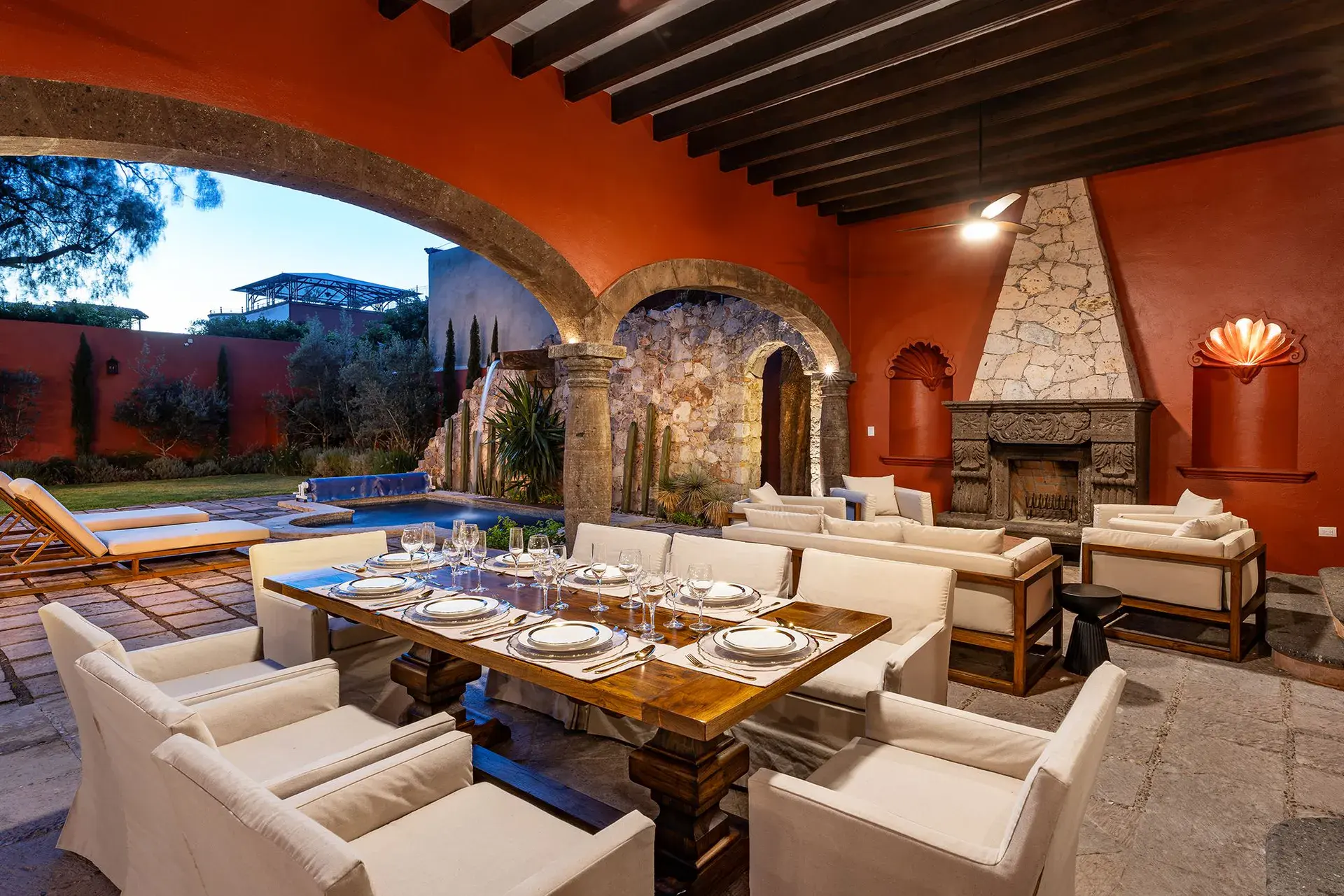 Casa Del Cardo, outdoor dining area beside a stone fireplace under an arch, San Miguel de Allende