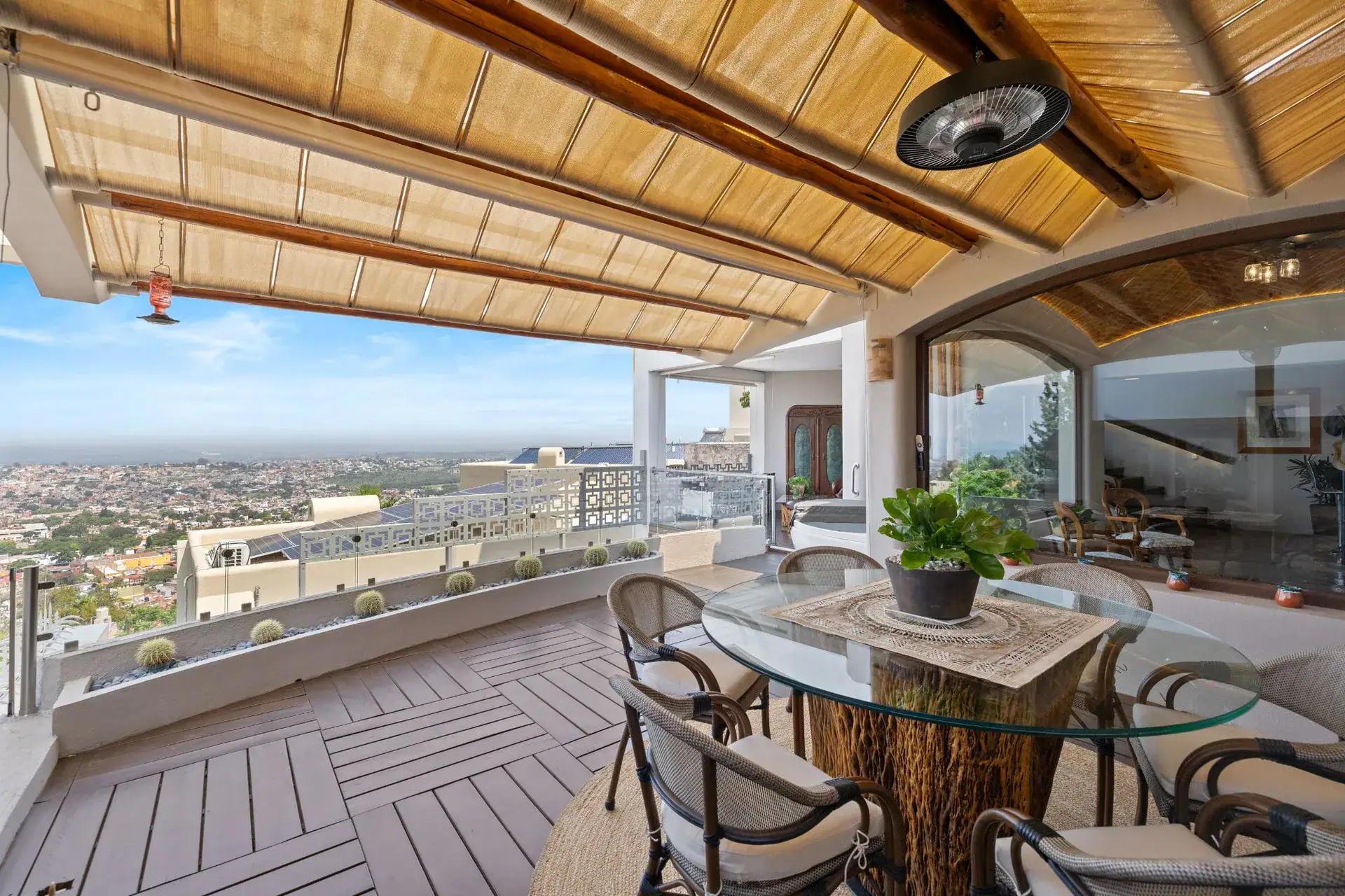 Casa del Foro, covered terrace with a glass-top round table and wicker chairs under a bamboo ceiling with a view over San Miguel