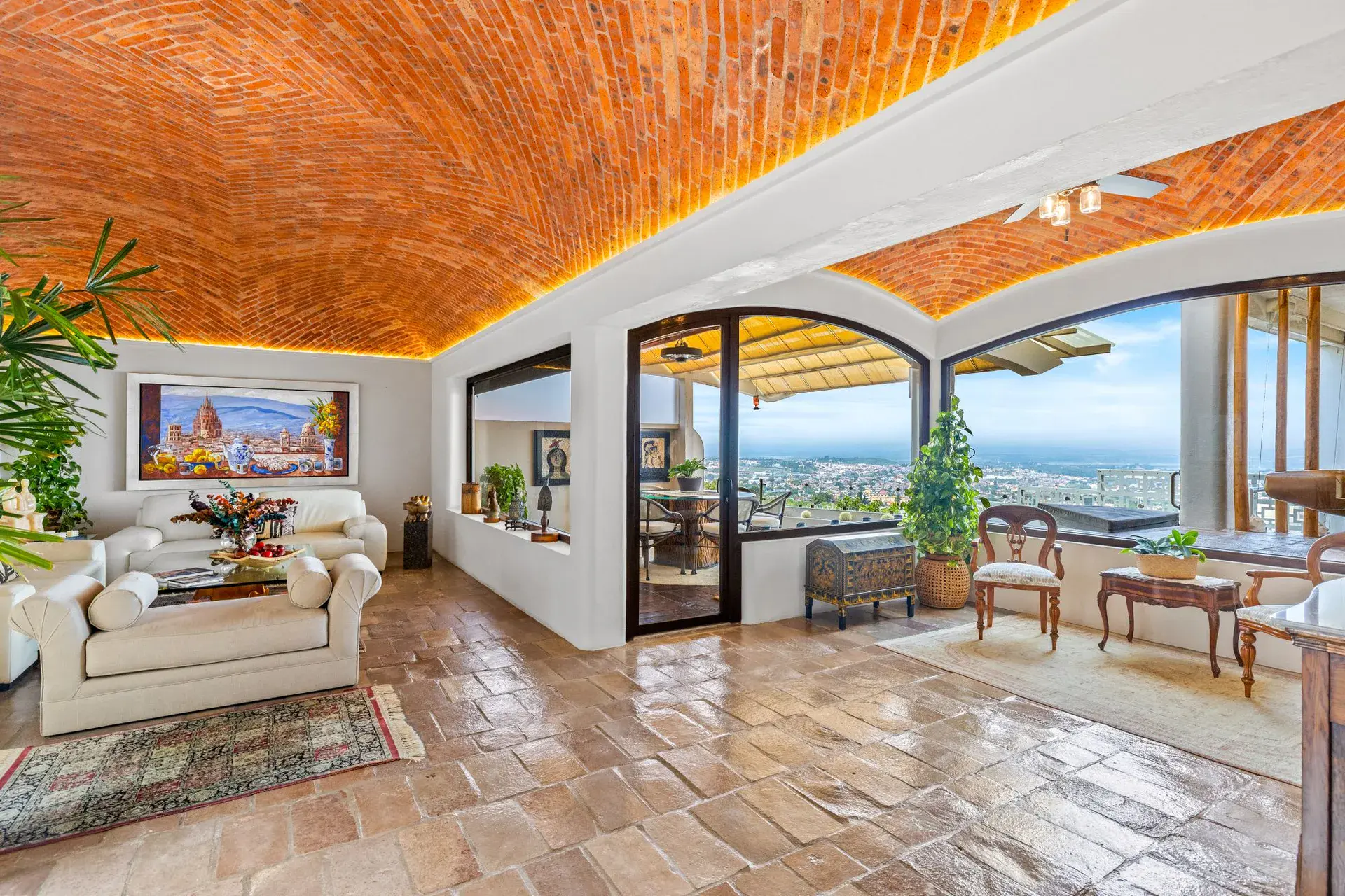 Casa del Foro, living room with cream sofas, a brick vaulted ceiling and glass walls to the terrace and the view, San Miguel de Allende