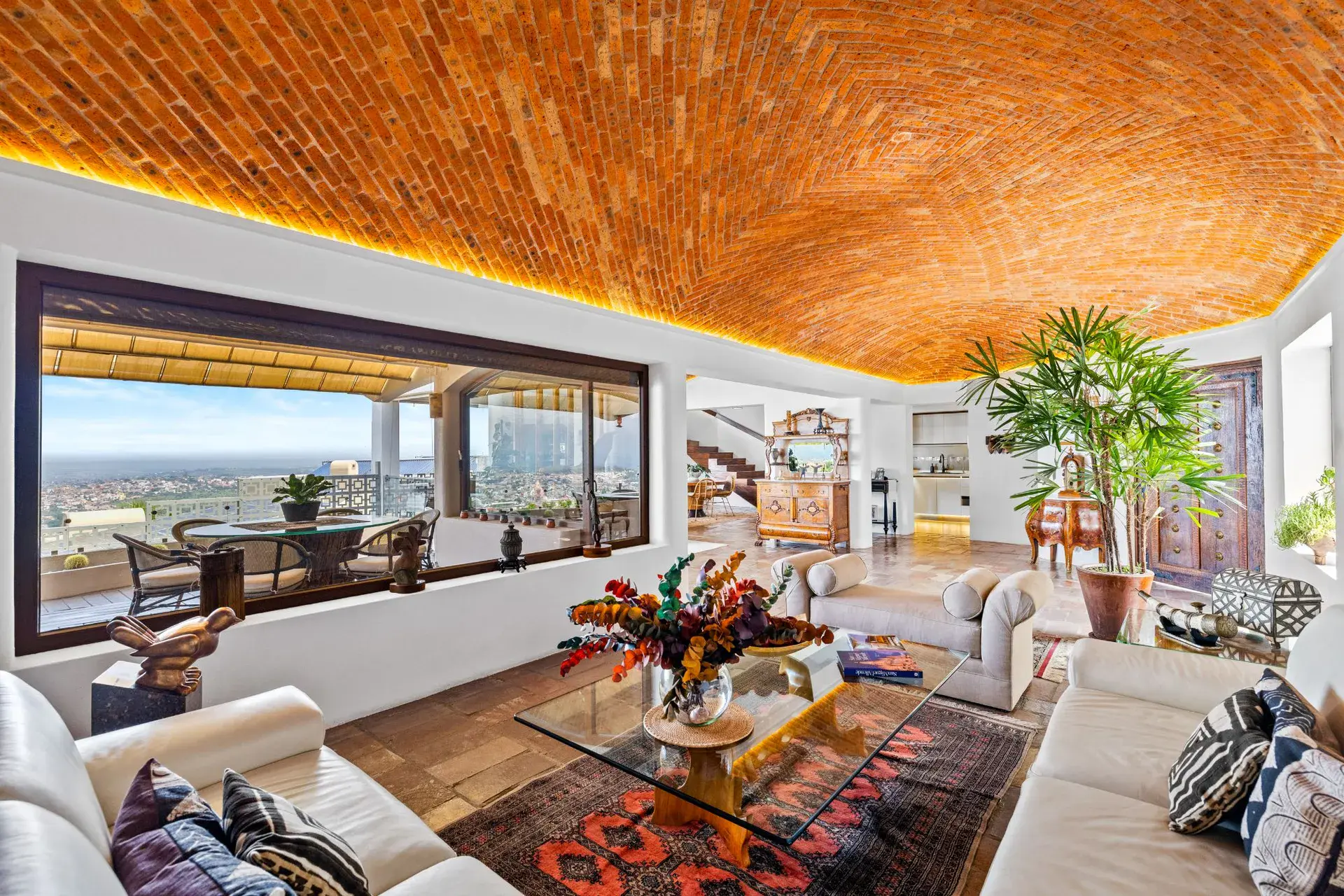 Casa del Foro, living room with a glass coffee table, a brick vaulted ceiling and a wall of glass facing the town, San Miguel de Allende