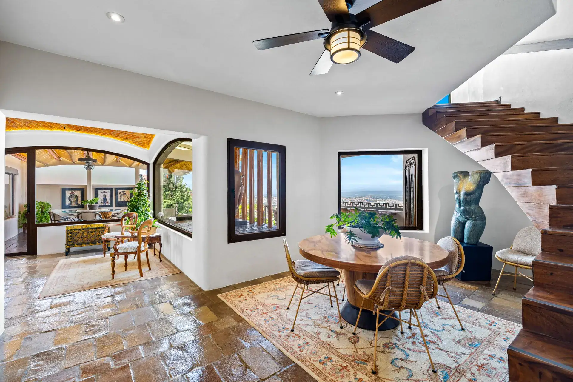 Casa del Foro, dining nook with a round table, a torso sculpture, a wood staircase and a window with a view, San Miguel de Allende